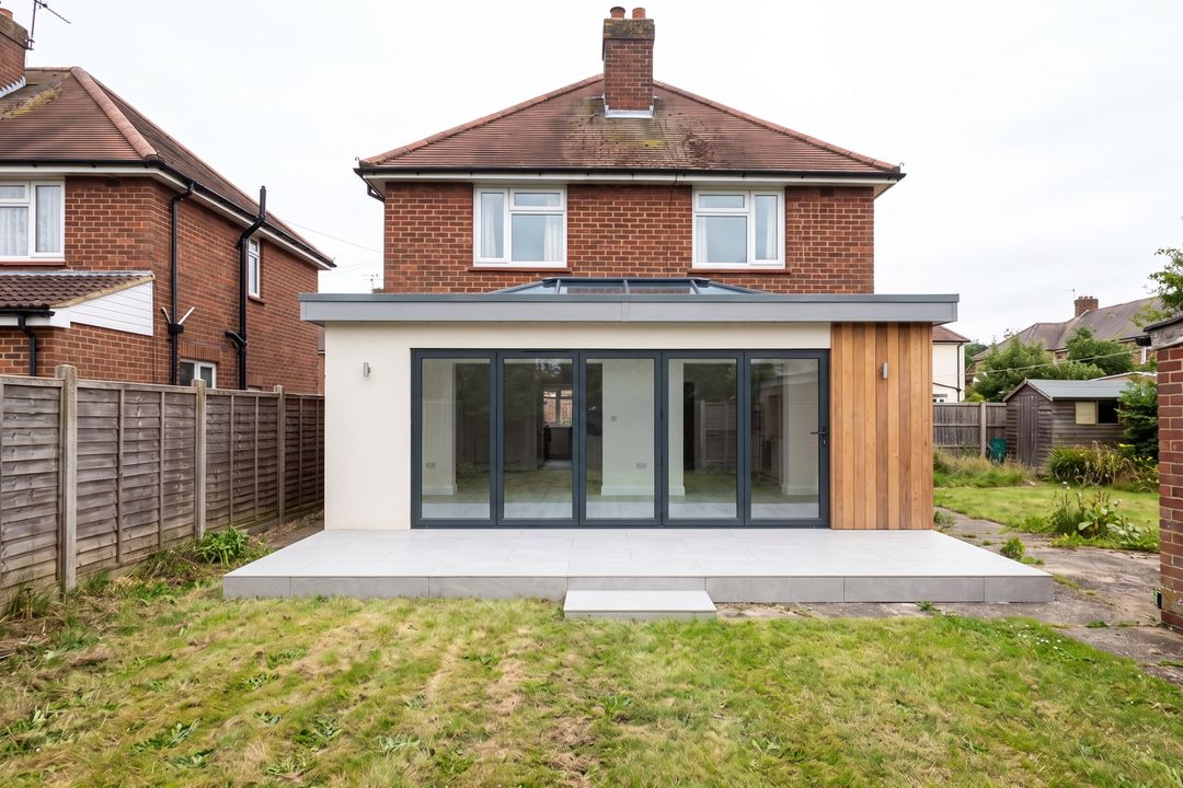 After concept: the same house with a single-storey extension, bifold doors, a roof lantern, white render and cedar cladding.